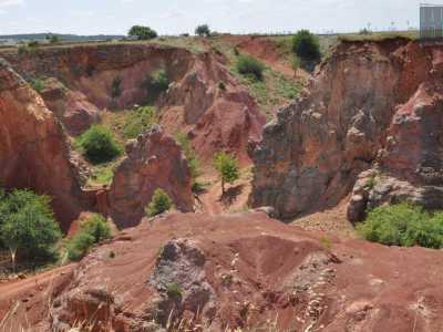 Ci basta per� percorrere qualche metro per ammirare finalmente la cava principale, dall�alto. Il paesaggio � ipnotico: le pareti rosse, valorizzate dal verde della vegetazione e arricchite dall�azzurro del cielo, ci trasportano in un mondo visivamente inedito, dominato da un�incantevole armonia cromatica